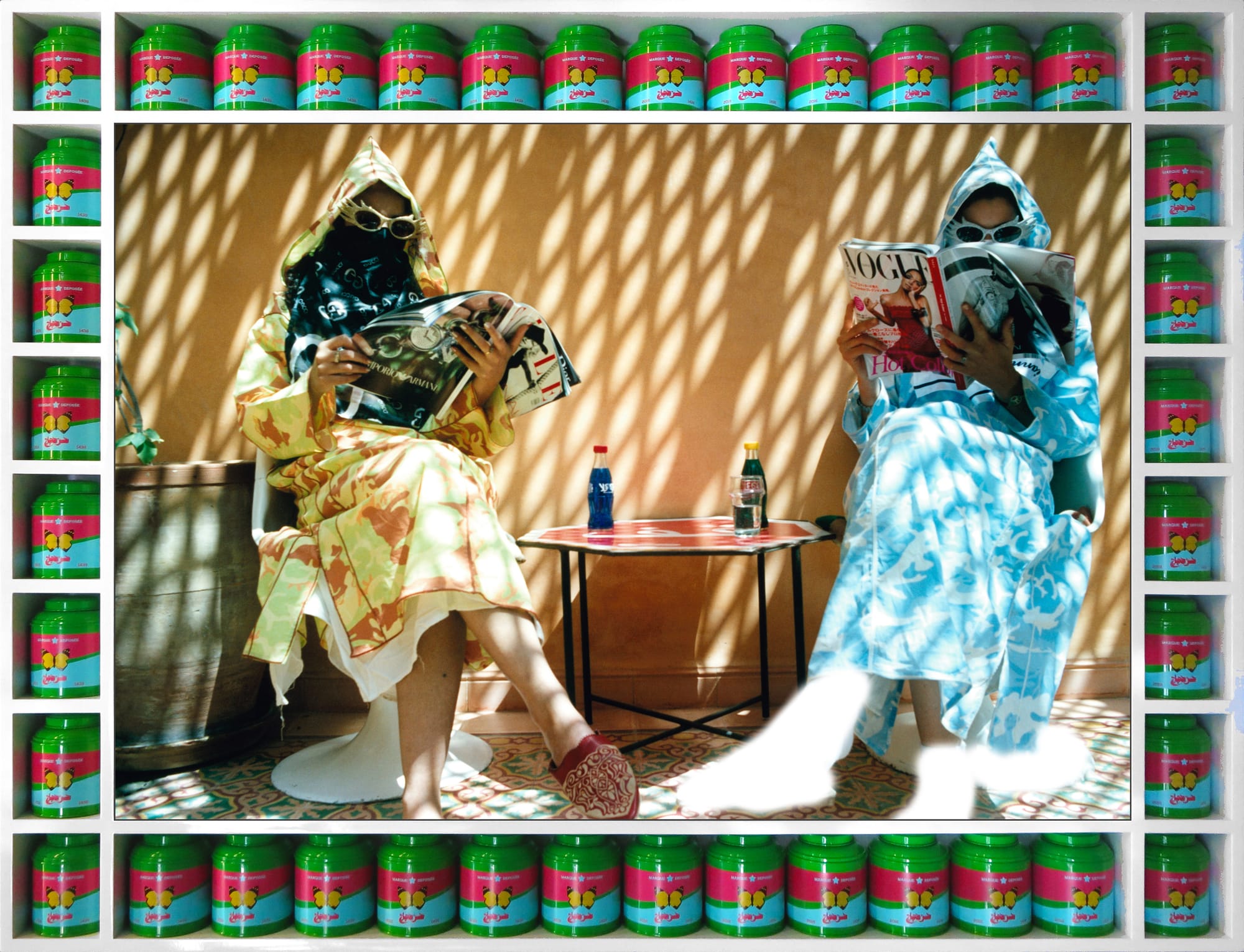 Dos mujeres con chilabas estampadas leen revistas de moda en un patio de Marrakech, en un marco hecho con botes de té