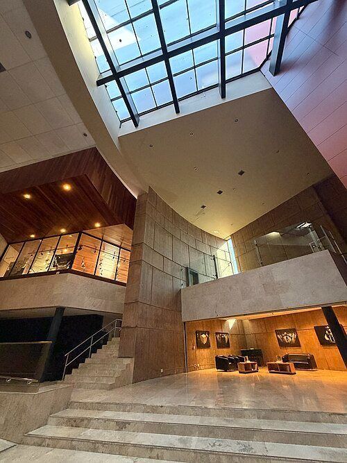 Vestíbulo del Centro Cultural Tijuana: escalera de piedra, madera y una gran cubierta acristalada